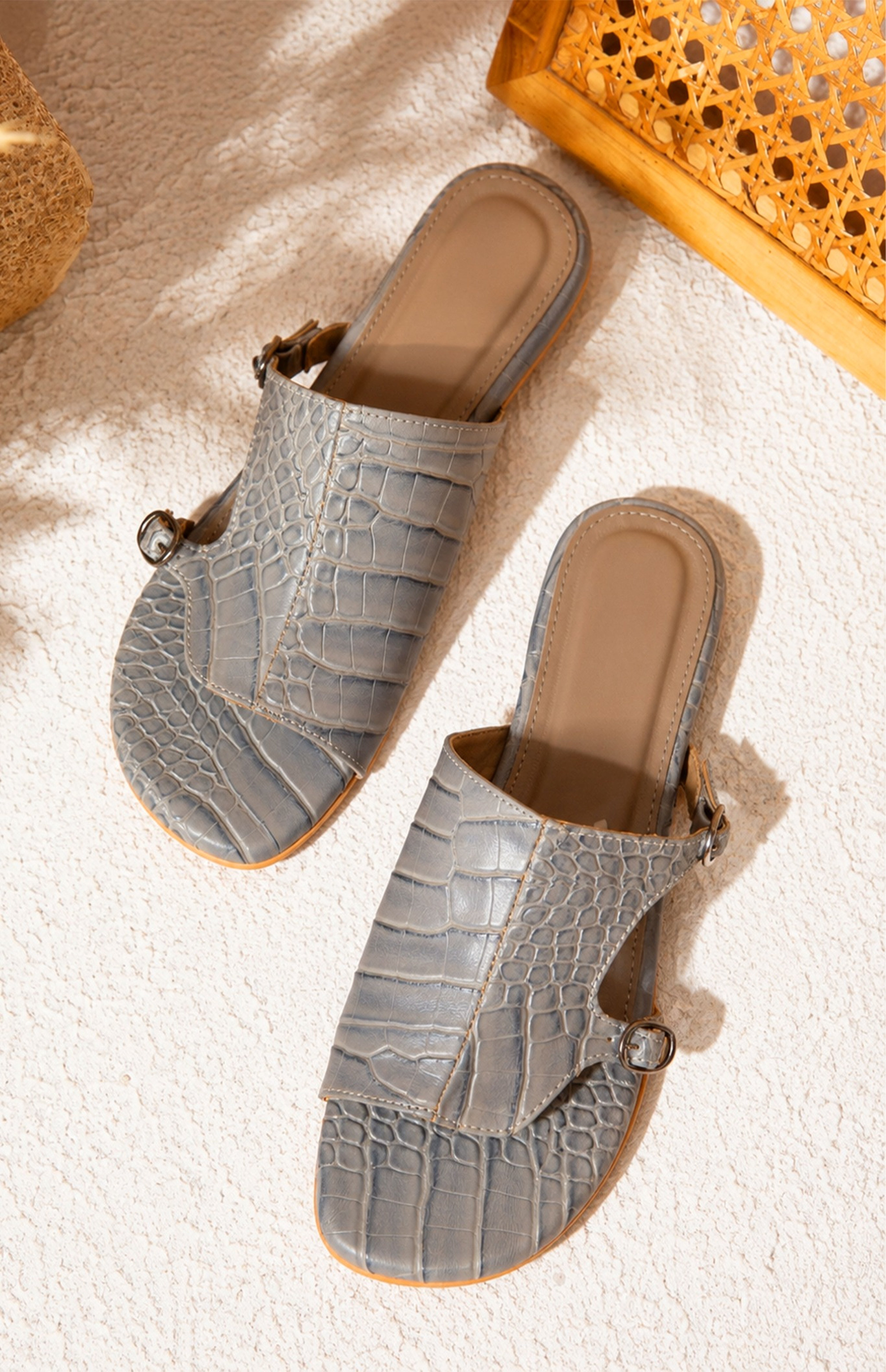 Pair of gray sandals with a textured pattern on a textured surface.